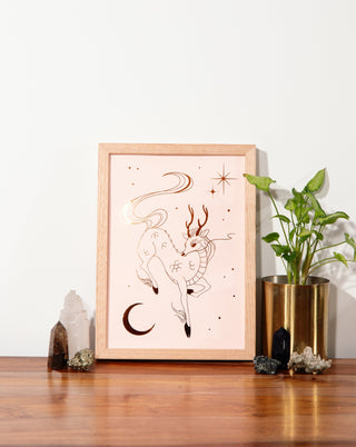 A framed qilin art print on a wooden table with crystals and pot plant.