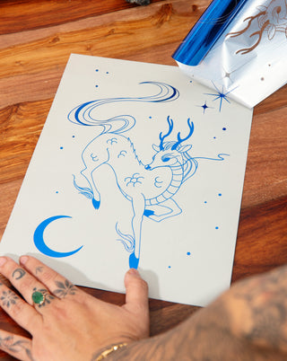 Foil art print of a blue qilin on a wooden table.