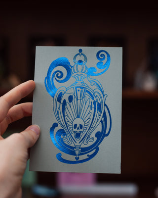 Hand holding a card with blue design against a blurred indoor background