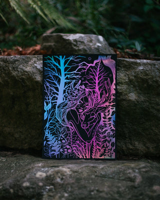 A black art print with a colourful holographic silver foil line-art illustration of a woman surrounded by trees, standing upright on stone steps outdoors.