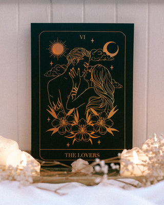 Decorative card titled 'The Lovers' with celestial design on a tray with candles.