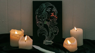 Candlelit scene with a goddess Medusa artwork on a black surface.