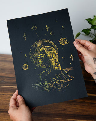 Moonlight Dip art print in holographic gold foil on black card, a woman gliding through water beneath the stars