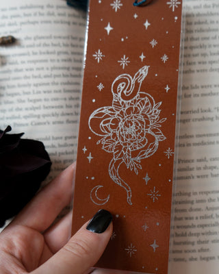 Decorative snake bookmark with celestial design on an open book
