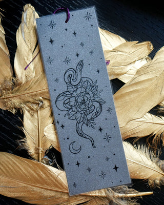 Decorative bookmark with a snake and floral design on feathers
