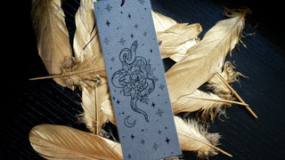 Decorative bookmark with a snake and floral design on feathers