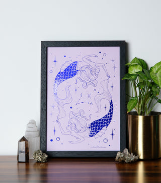 Framed artwork of a mermaid on a table with decorative items and a plant.
