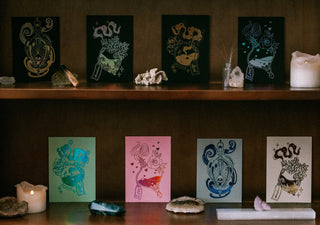 Decorative cards on a wooden shelf with candles and small figurines.