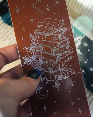 Hand holding a brown and silver bookmark