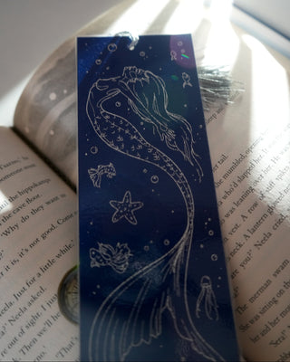 Navu blue siren bookmark with tassle on an open book.