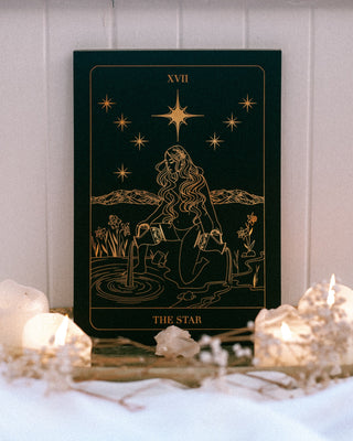 The Star tarot print design on a table with candles and flowers.