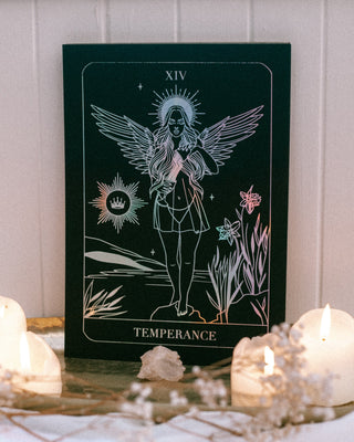 Tarot card titled 'Temperance' with candles and crystals on a wooden surface