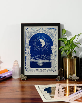 Framed tarot artwork on a wooden surface with decorative items.