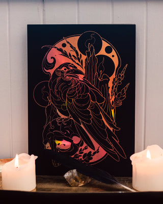 Decorative wall art with a raven design on a dark background, illuminated by candles.