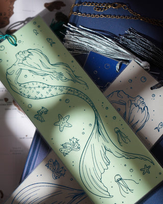 Green book with mermaid design on a blue surface with text